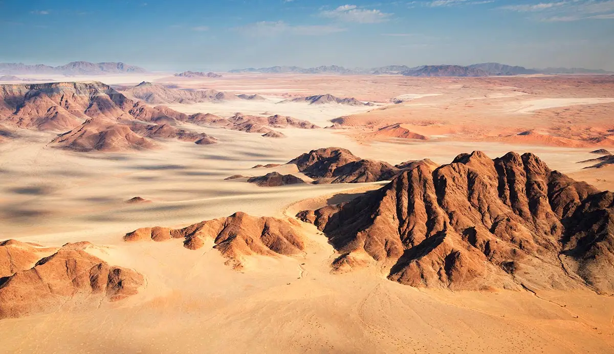 Ein Blick von oben auf die rötliche Felsenlandschaft im Namib-Naukluft Nationalpark.