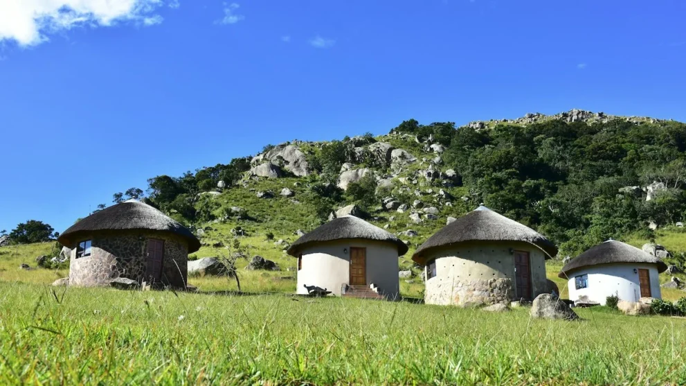 Rundhütten mit Strohdach vor einem Granithügel in Eswatini