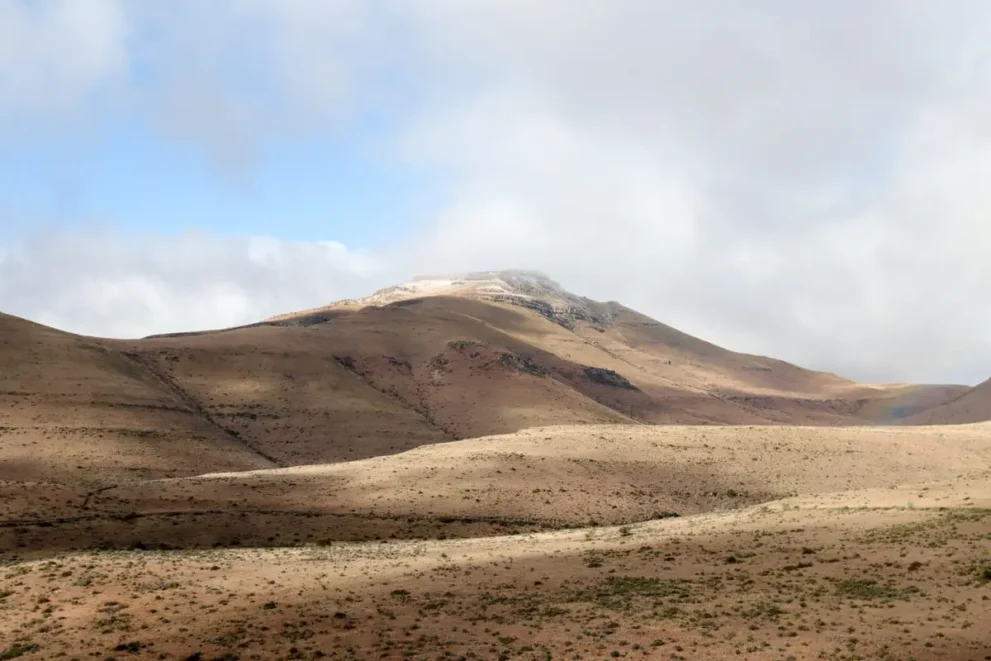 Karges, hügeliges Wüstenland mit bewölktem Himmel und leichtem Blau im Hintergrund.