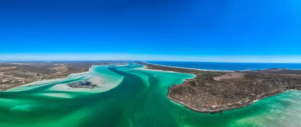 Küste mit türkisfarbenem Wasser und Landzunge unter strahlend blauem Himmel. Atemberaubende Landschaftspanorama.