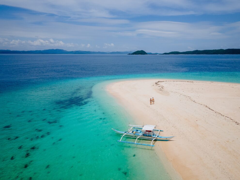 Weiße Sandbank von North Cay bei Busuanga mit Auslegerboot im türkisfarbenen Flachwasser, Calamian-Inseln, Palawan