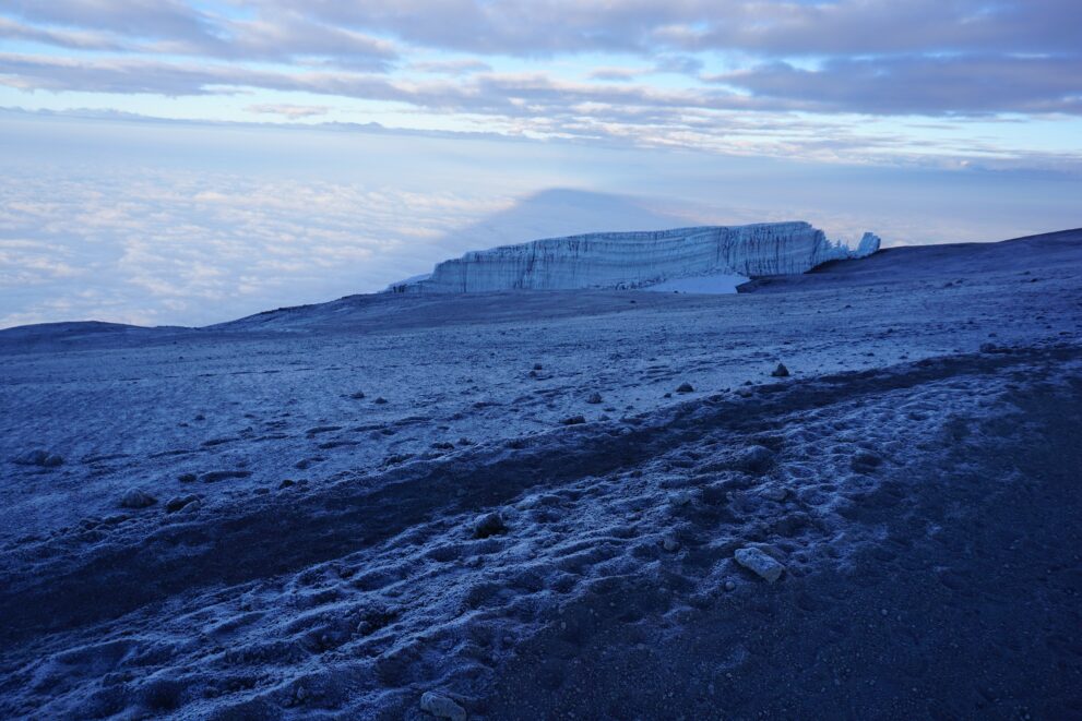 Eisfelder am Gipfel des Kilimandscharo im ersten Morgenlicht, darunter ein Wolkenmeer