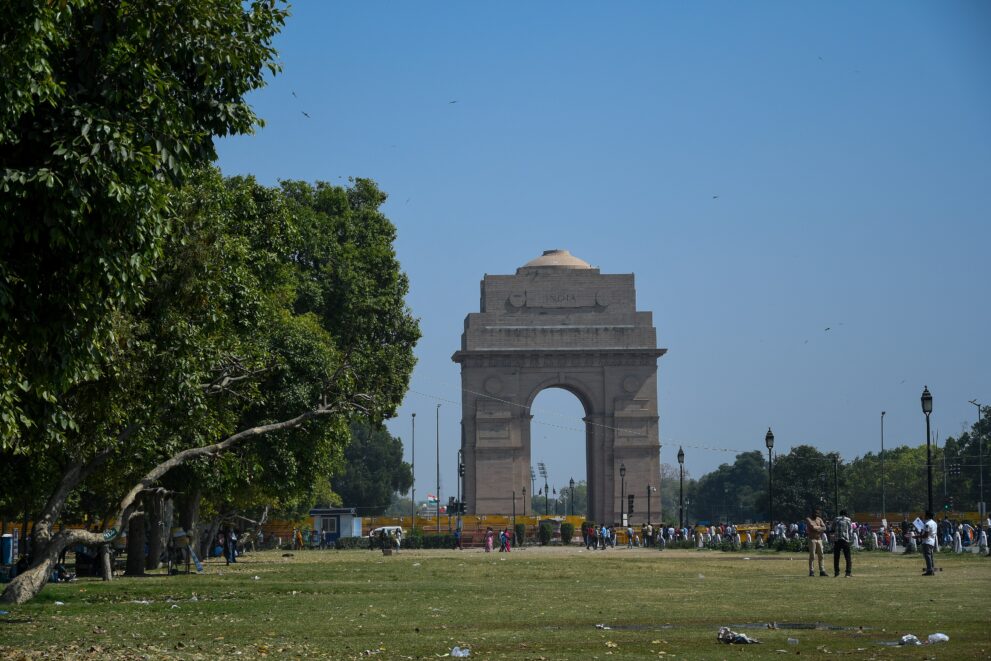 Das India Gate in Neu-Delhi am Ende der Rasenflächen, im Vordergrund Bäume, Besucher nur klein