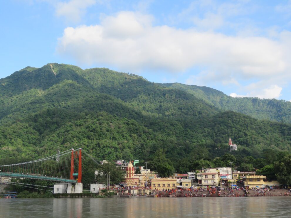 Ram Jhula und die Ghats von Swargashram am Ganges in Rishikesh unter bewaldeten Bergen