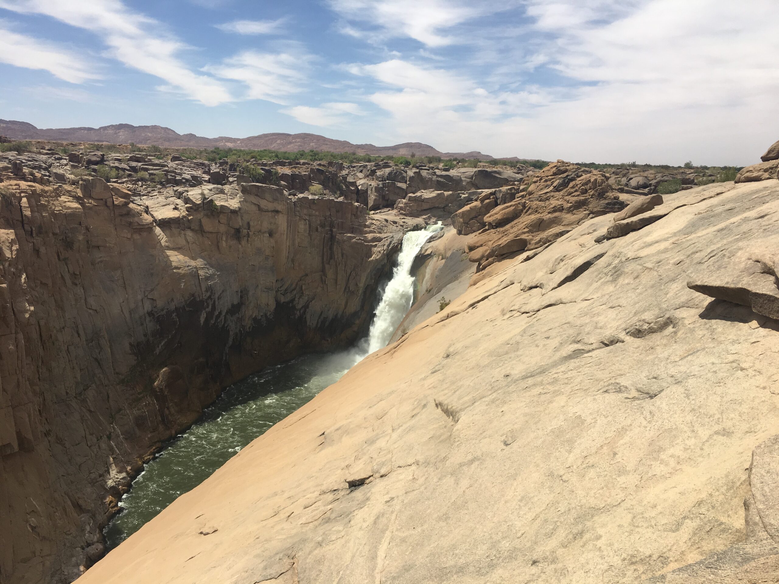 Der Augrabies-Wasserfall als schmaler Strahl in der Granitschlucht, im Vordergrund glatter Fels, aufgenommen im Oktober 2019