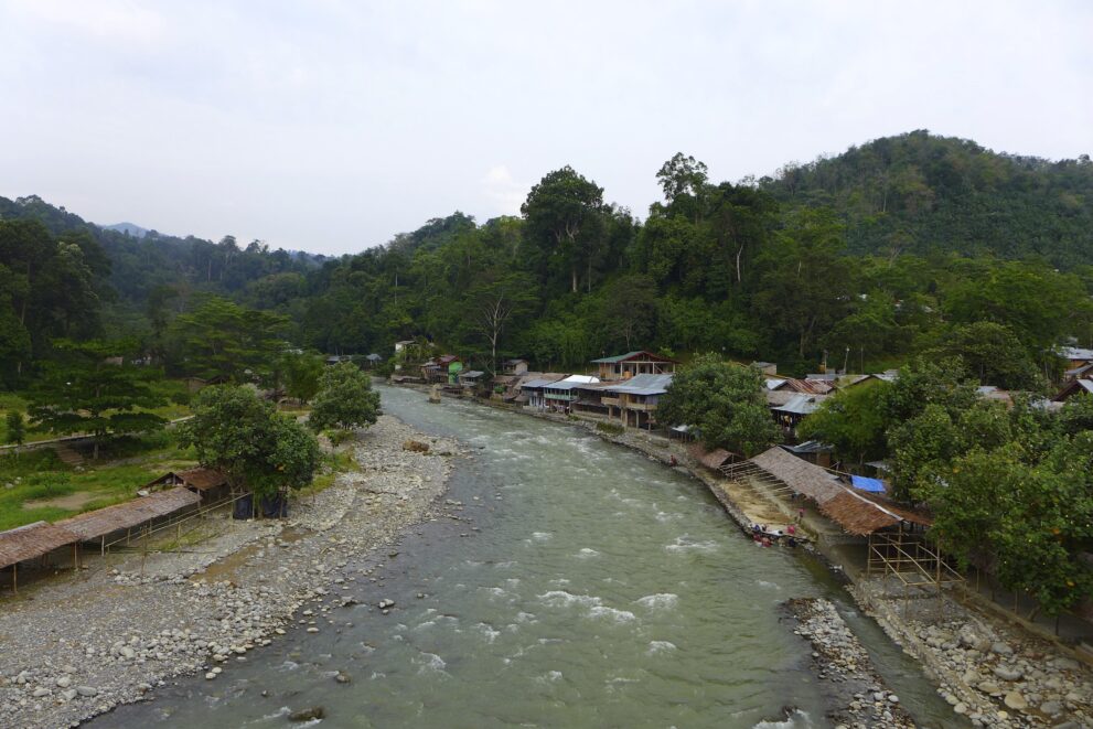 Dorf Bukit Lawang am Ufer des Bahorok-Flusses, dahinter die bewaldeten Hügel des Gunung-Leuser-Nationalparks auf Sumatra