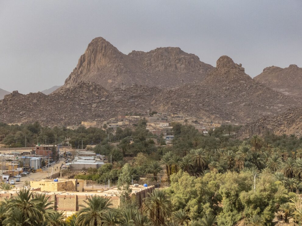 Blick auf den Ksar Azelouaz und die Palmen der Oase Djanet vor einem markanten Felsberg