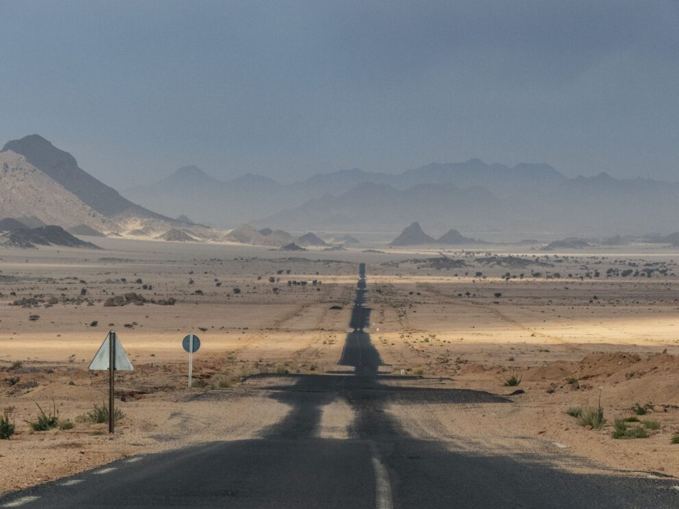 Asphaltstraße von Djanet in Richtung Roter Tadrart, gerade durch die Ebene bis zu fernen Bergen