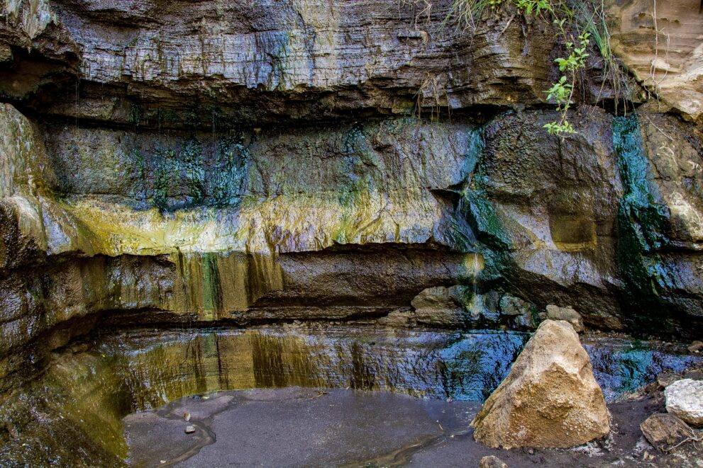 Heiße Quelle mit farbigen Mineralablagerungen an der Felswand der Schlucht im Hell's-Gate-Nationalpark