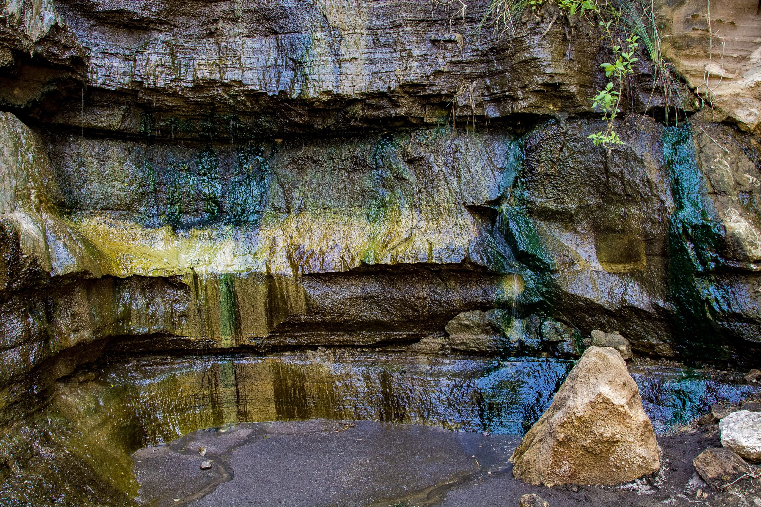 Heiße Quelle mit farbigen Mineralablagerungen an der Felswand der Schlucht im Hell's-Gate-Nationalpark