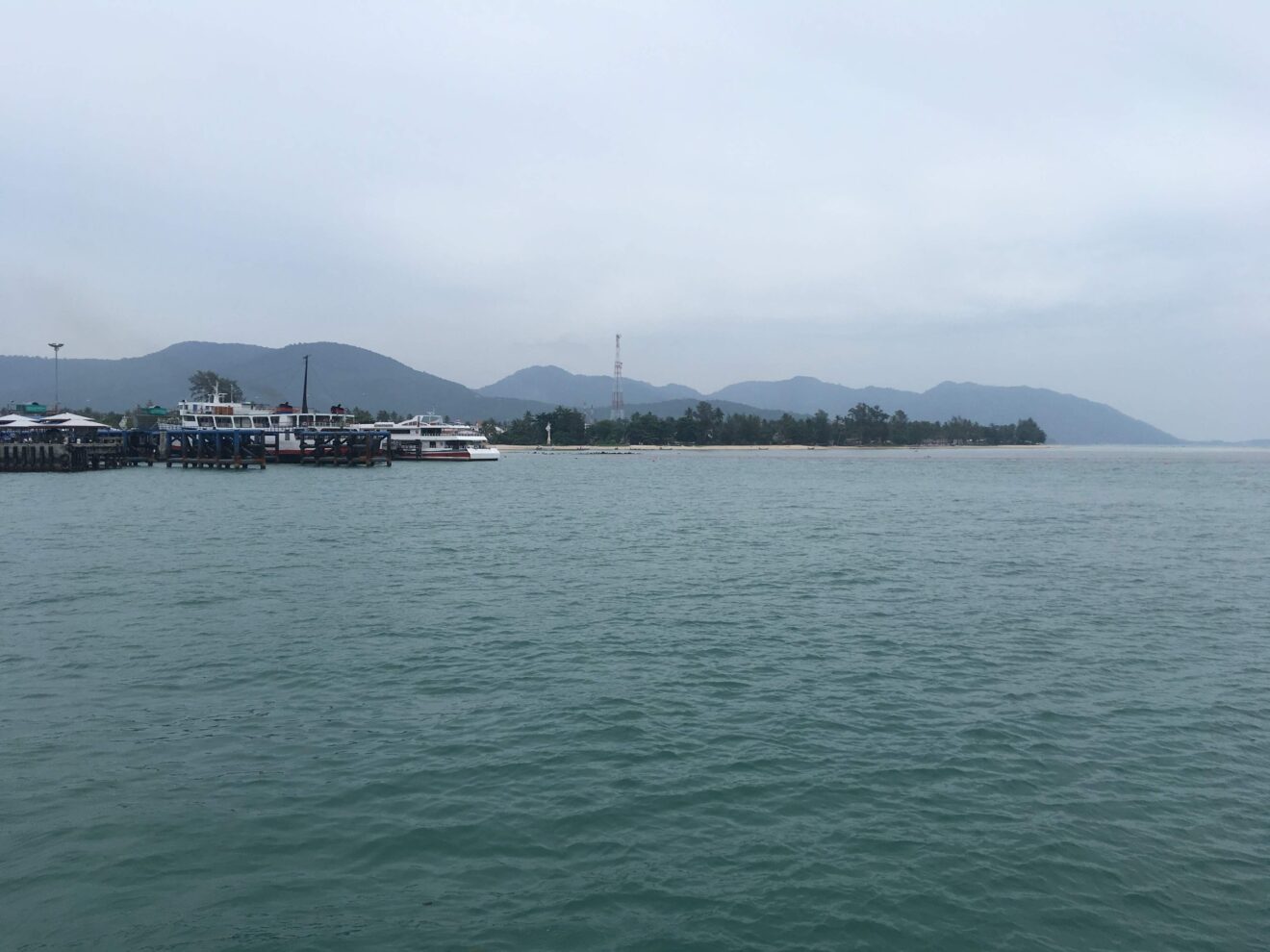 Blick von der Fähre aus Koh Samui auf die Küste von Koh Phangan mit Anlegestelle und Bergen im Hintergrund