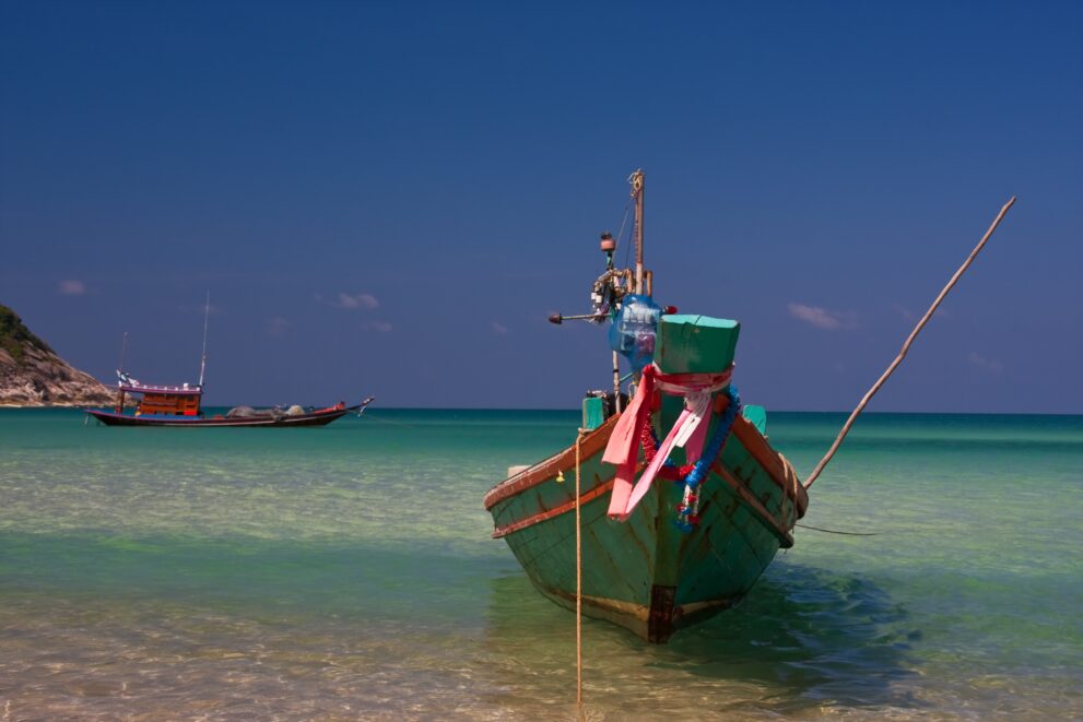 Bunt geschmücktes Longtailboot im flachen, klaren Wasser vor Bottle Beach auf Koh Phangan