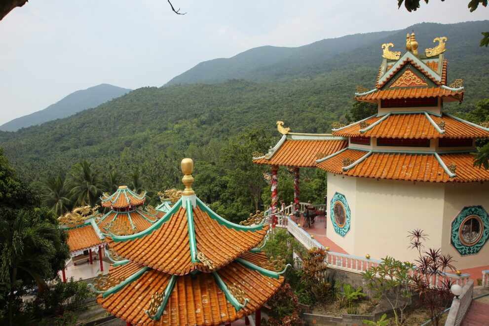 Chinesischer Schrein Chao Mae Kuan Im mit geschwungenen Dächern vor den Regenwaldhügeln von Koh Phangan