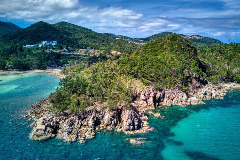 Felsige Landspitze mit Dschungel und klarem türkisfarbenem Wasser an der Küste von Koh Phangan