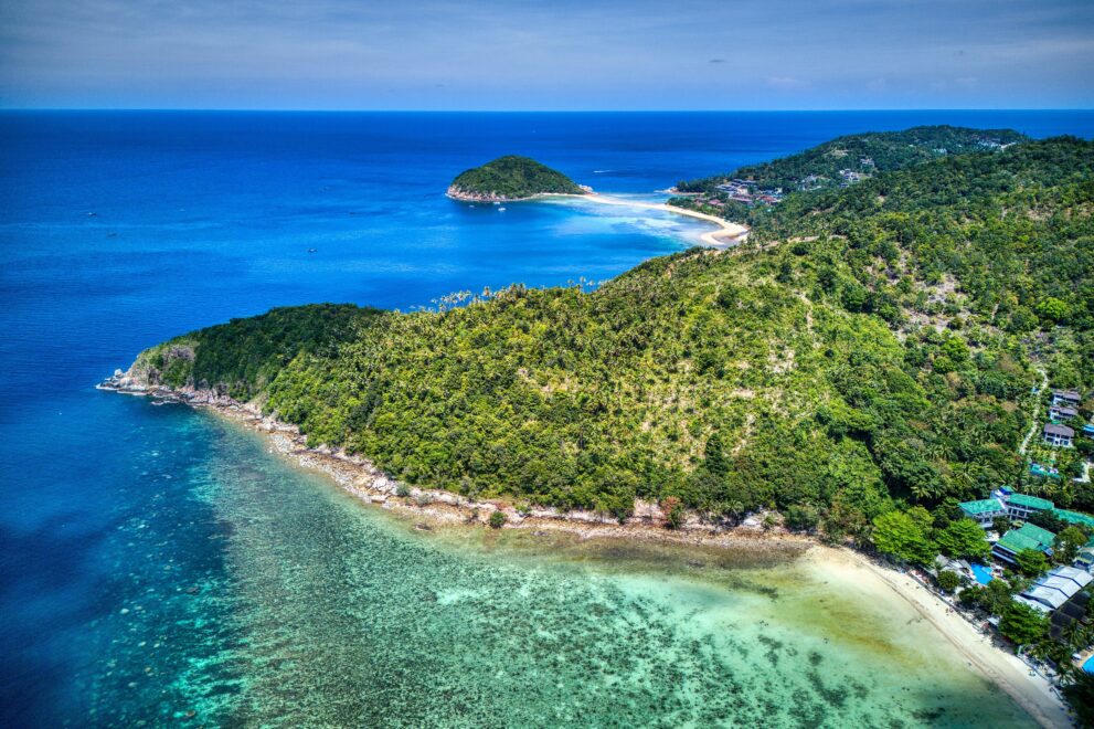 Luftbild einer bewaldeten Landzunge von Koh Phangan mit Korallenriff, Sandstrand und türkisfarbenem Meer