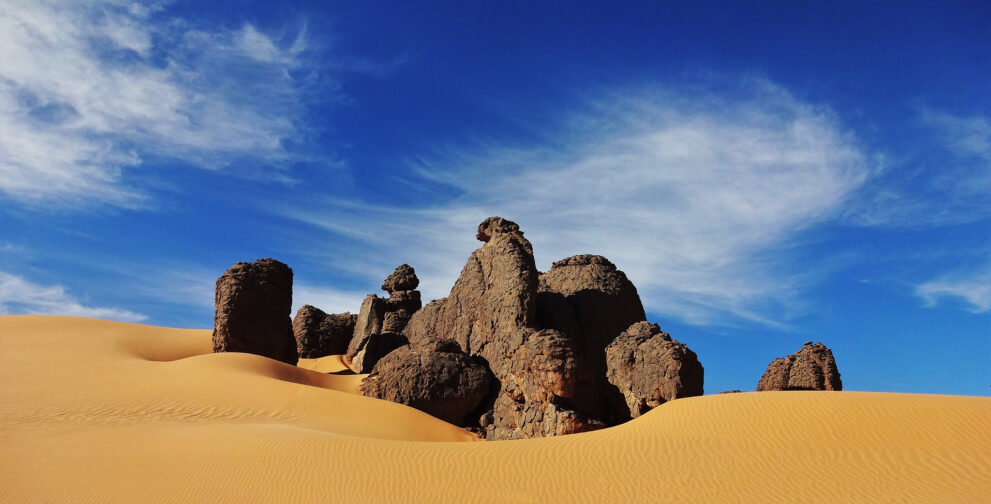Sandsteinfelsen in einer goldenen Düne hoch im Tassili n Ajjer unter blauem Himmel