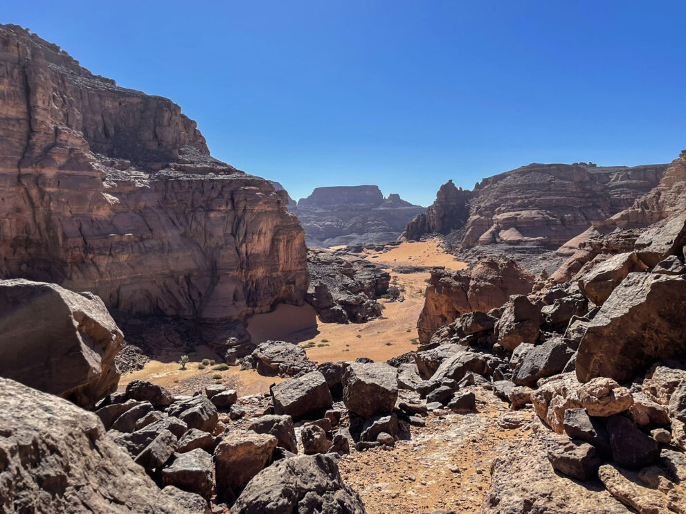 Blick in den Canyon Tissatka mit Felsblöcken und Sandgrund zwischen hohen Wänden im Roten Tadrart