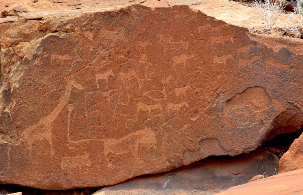 Felsgravuren von Twyfelfontein in Namibia: die Löwenplatte mit Giraffe, Löwe und weiteren Tieren im roten Sandstein