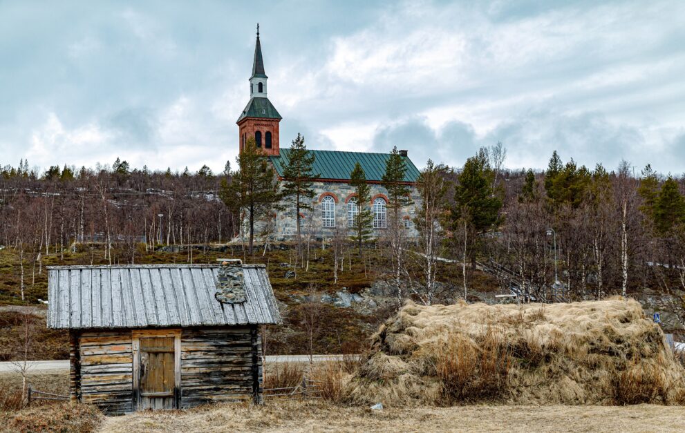 Steinkirche von Utsjoki aus dem Jahr 1853 hinter einer alten Kirchhütte im Kirchdorf