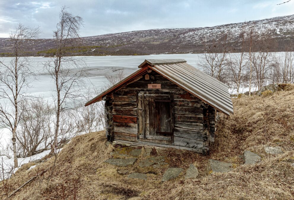 Alte Kirchhütte aus Holz am zugefrorenen See Mantojärvi im Kirchdorf von Utsjoki