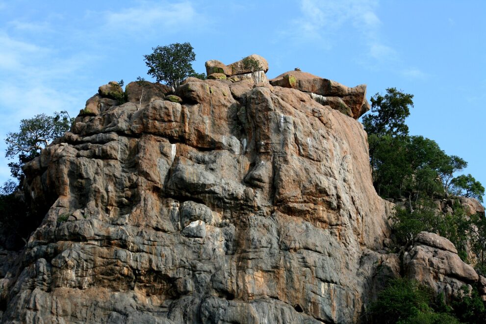 Hohe, verwitterte Granitwand mit Bäumen auf der Kuppe