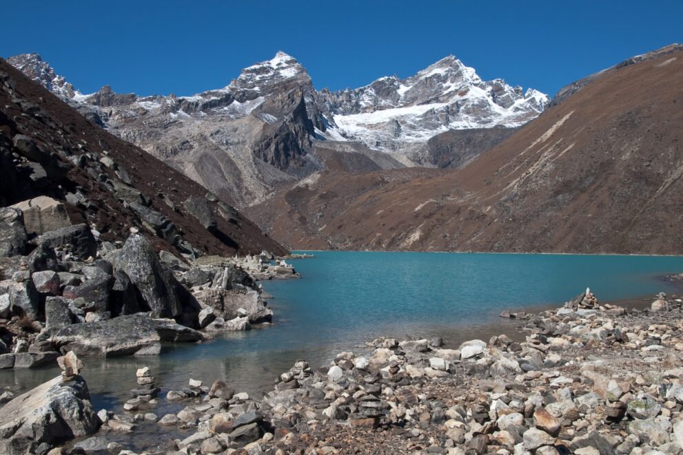 Der türkise Dudh Pokhari, dritter der Gokyo-Seen, mit Felsblöcken am Ufer