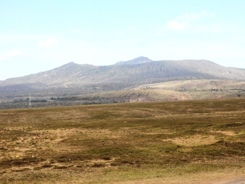 Der flache, breite Kegel des Mount Longonot hinter einer offenen Grasebene