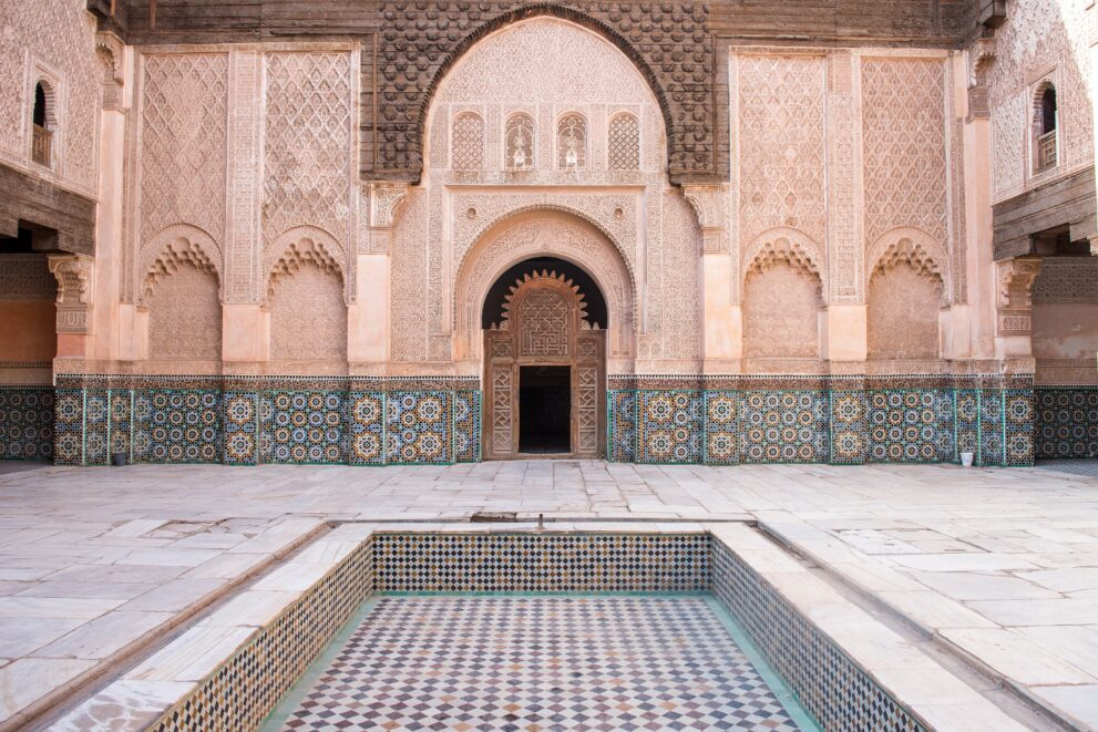 Innenhof der Medersa Ben Youssef in Marrakesch mit Wasserbecken, Zellige und geschnitztem Stuck