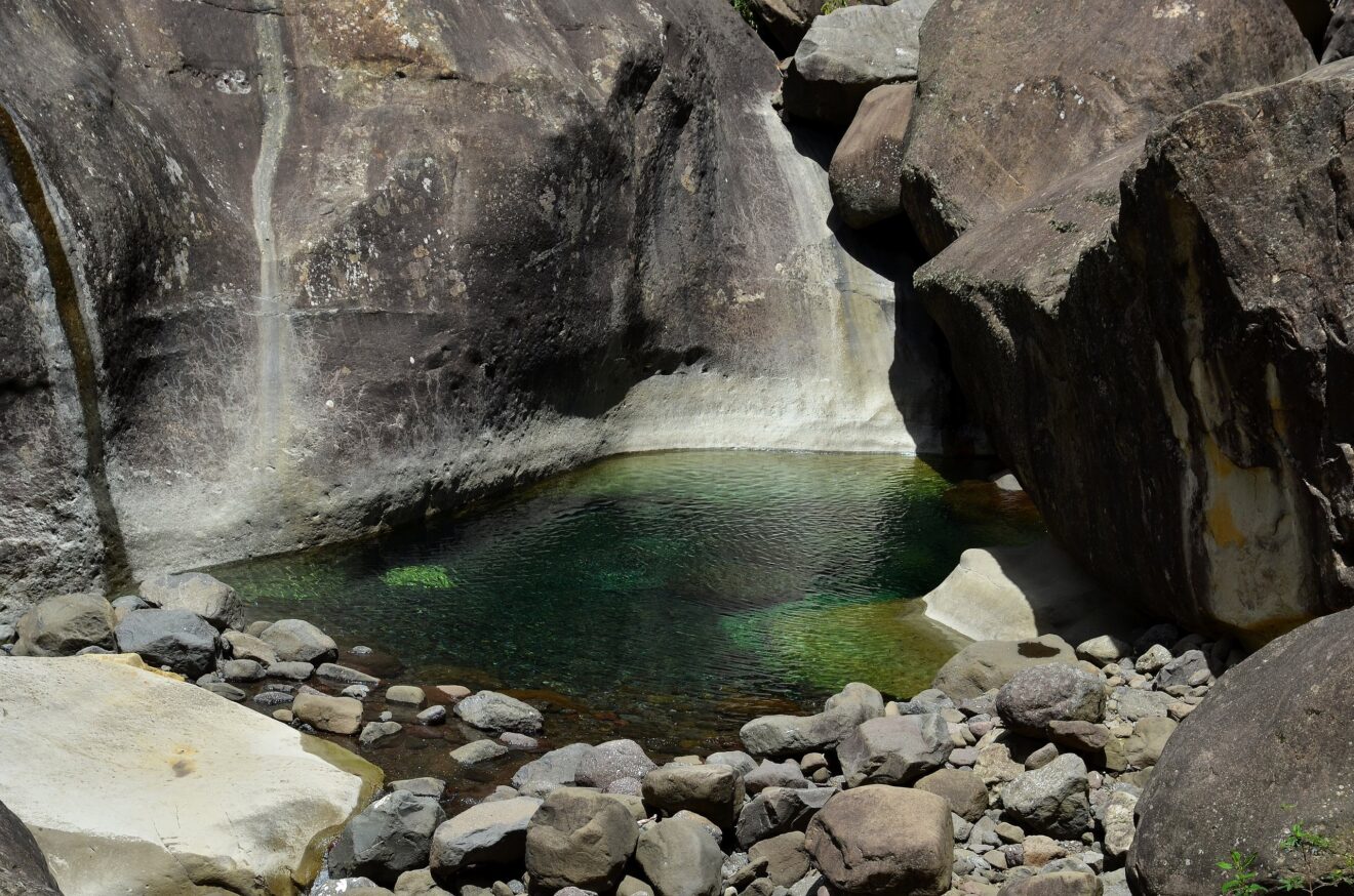 Grünes Felsbecken zwischen großen Felsblöcken und glatter Felswand in der Tugela-Schlucht